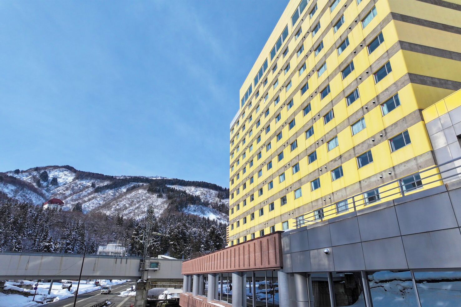 Un edificio de varios pisos con fachada amarilla y diseño arquitectónico moderno.