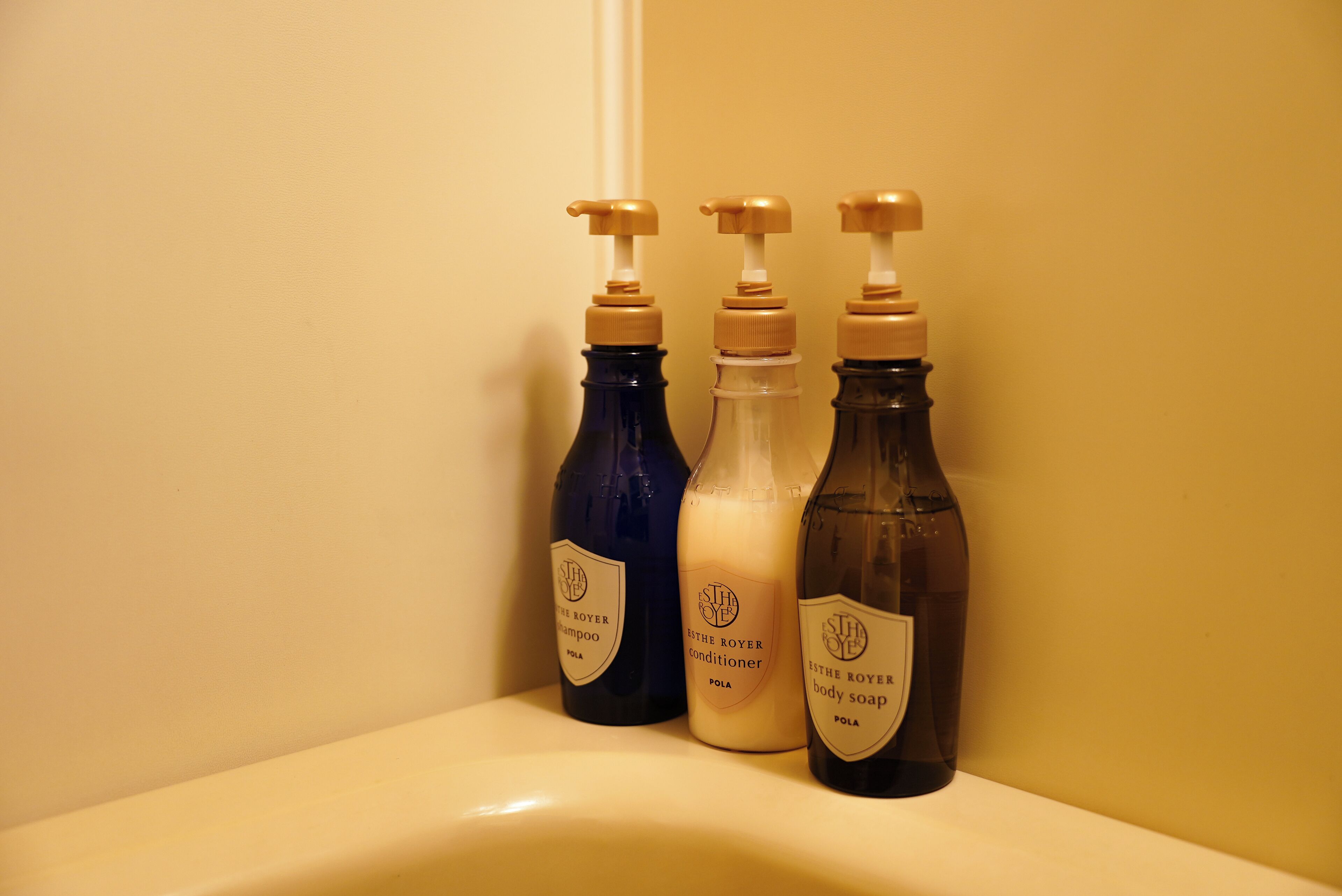Tres botellas de productos de cuidado corporal Estee Royale sobre una encimera de baño.