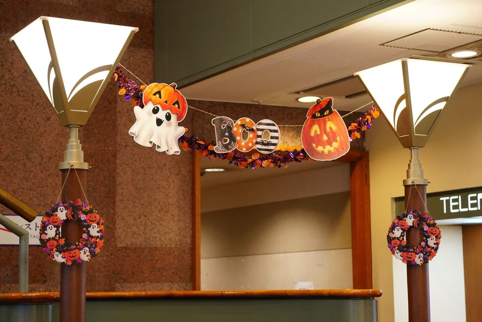 A hallway with Halloween decorations including a banner with the word 'BOO' and ghost and pumpkin cutouts.