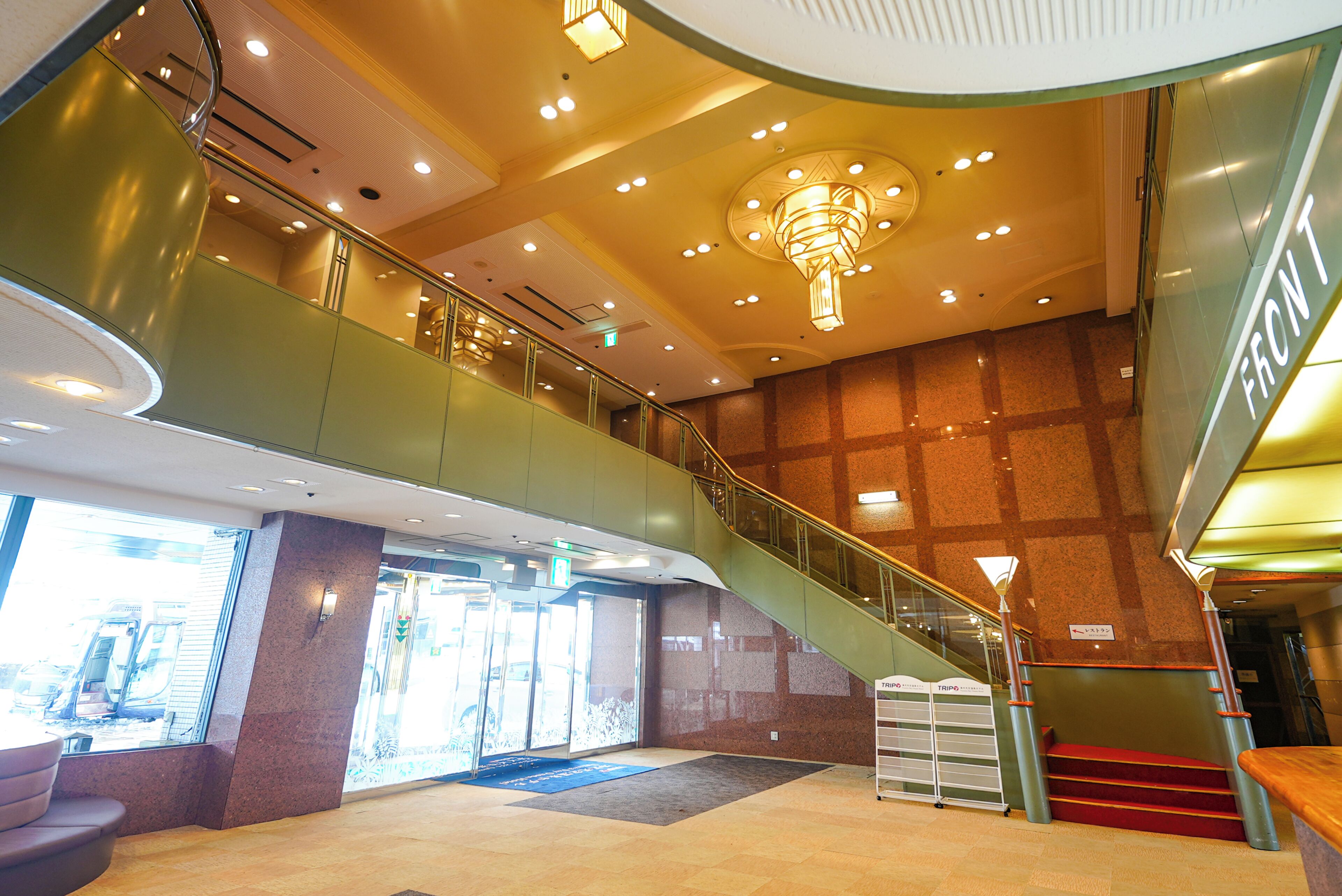 A modern interior with a curved staircase, a reception desk, and a view of the outside through large windows.