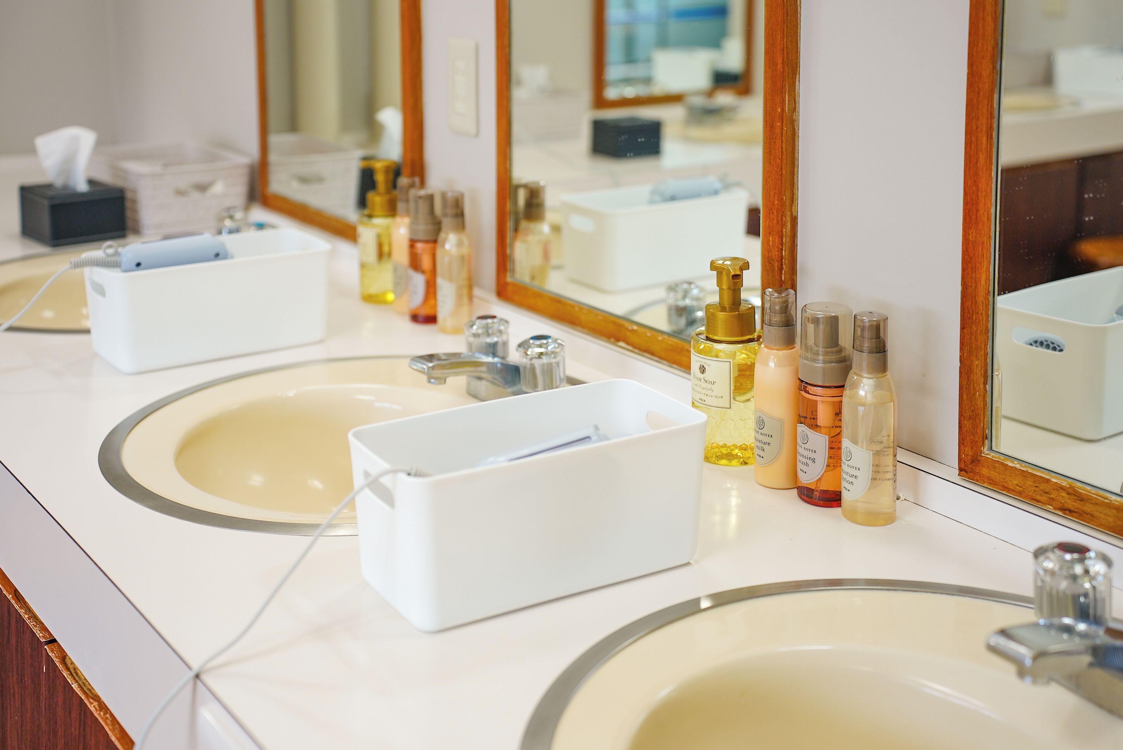 A bathroom with two sinks, a mirror, and various toiletries.