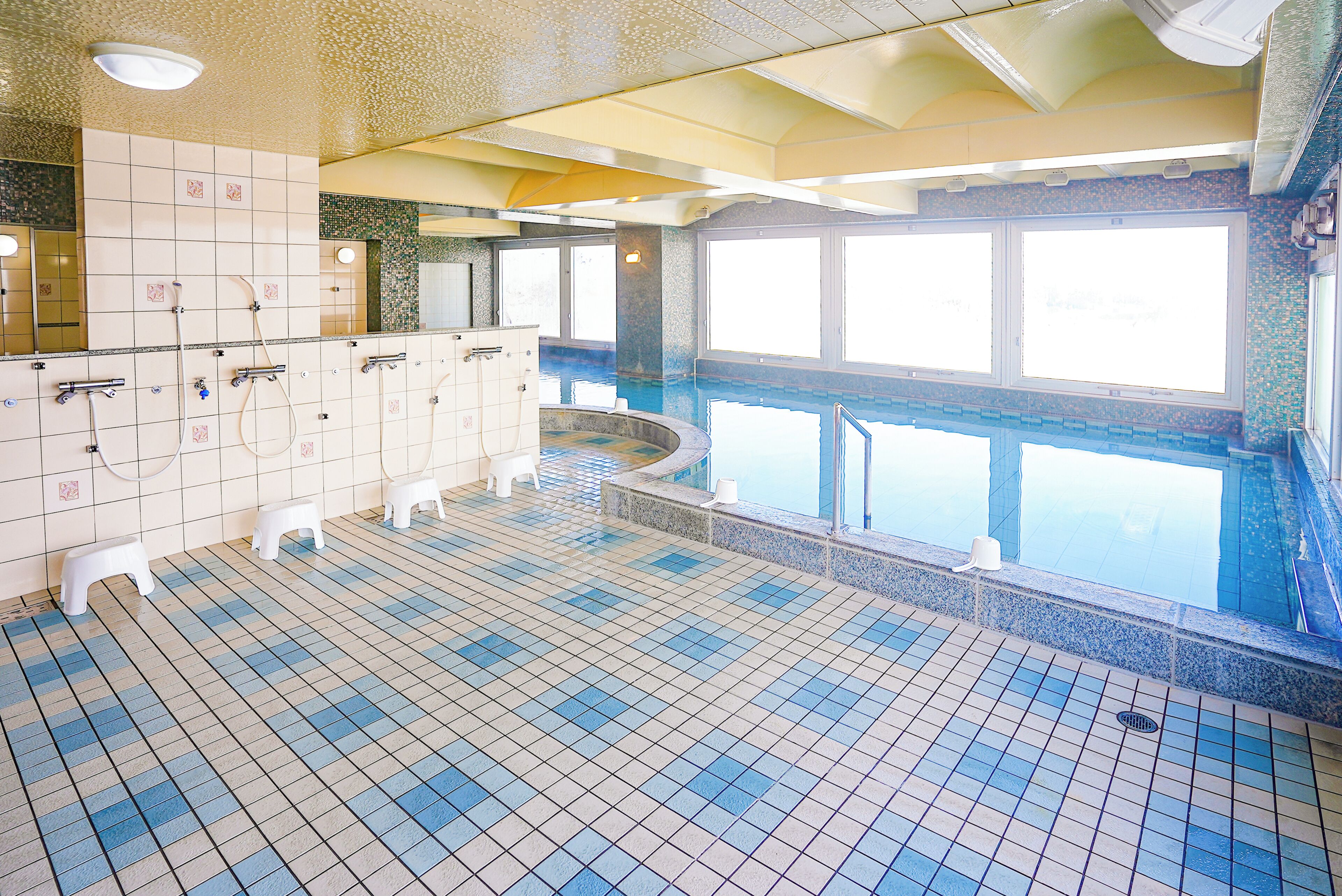 Una piscina con suelo de baldosas y un vestuario con taquillas.