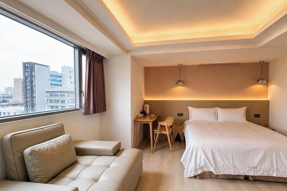 Een hotelkamer met een bed, een bank, een bureau en een stoel.