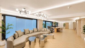 Un salon moderne avec un canapé aux lignes courbes, un coin repas et une grande fenêtre.