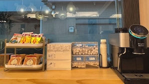Une machine à café, un plateau avec des en-cas et une boîte de mouchoirs sur un comptoir.