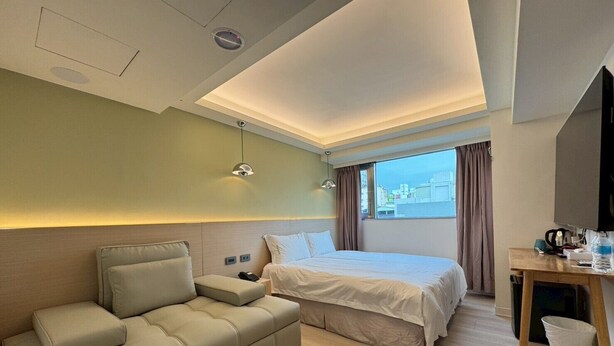 Une chambre d’hôtel moderne équipée d’un lit, d’un canapé, d’un bureau et offrant une vue sur la ville.