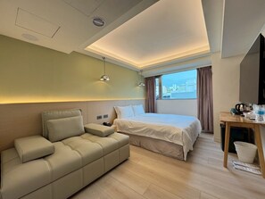 A modern hotel room with a bed, a sofa, a desk, and a view of the city. - Fooyee Hotel - tcstation (Taichung)