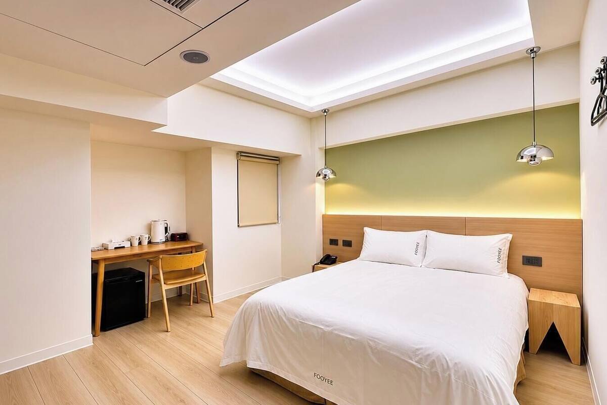 Een hotelkamer met een bed, bureau, stoel en een kleine kitchenette.