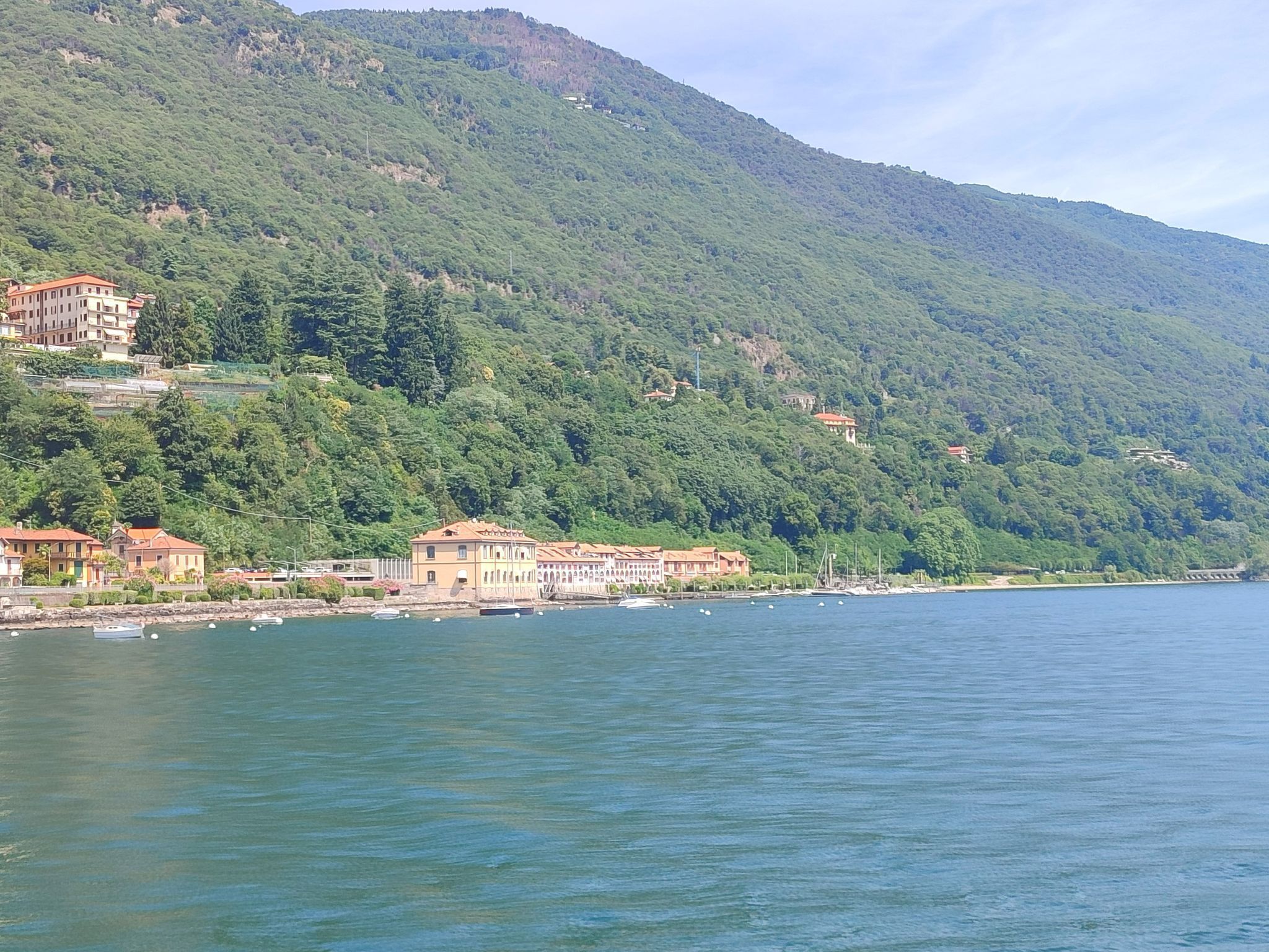 A coastal town with buildings along the shoreline, a mountain in the background, and calm water.