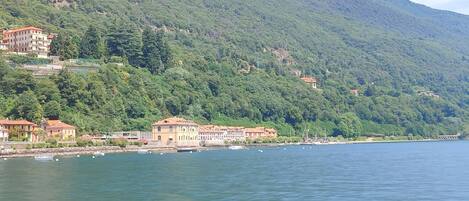A coastal town with buildings along the shoreline, a mountain in the background, and calm water.