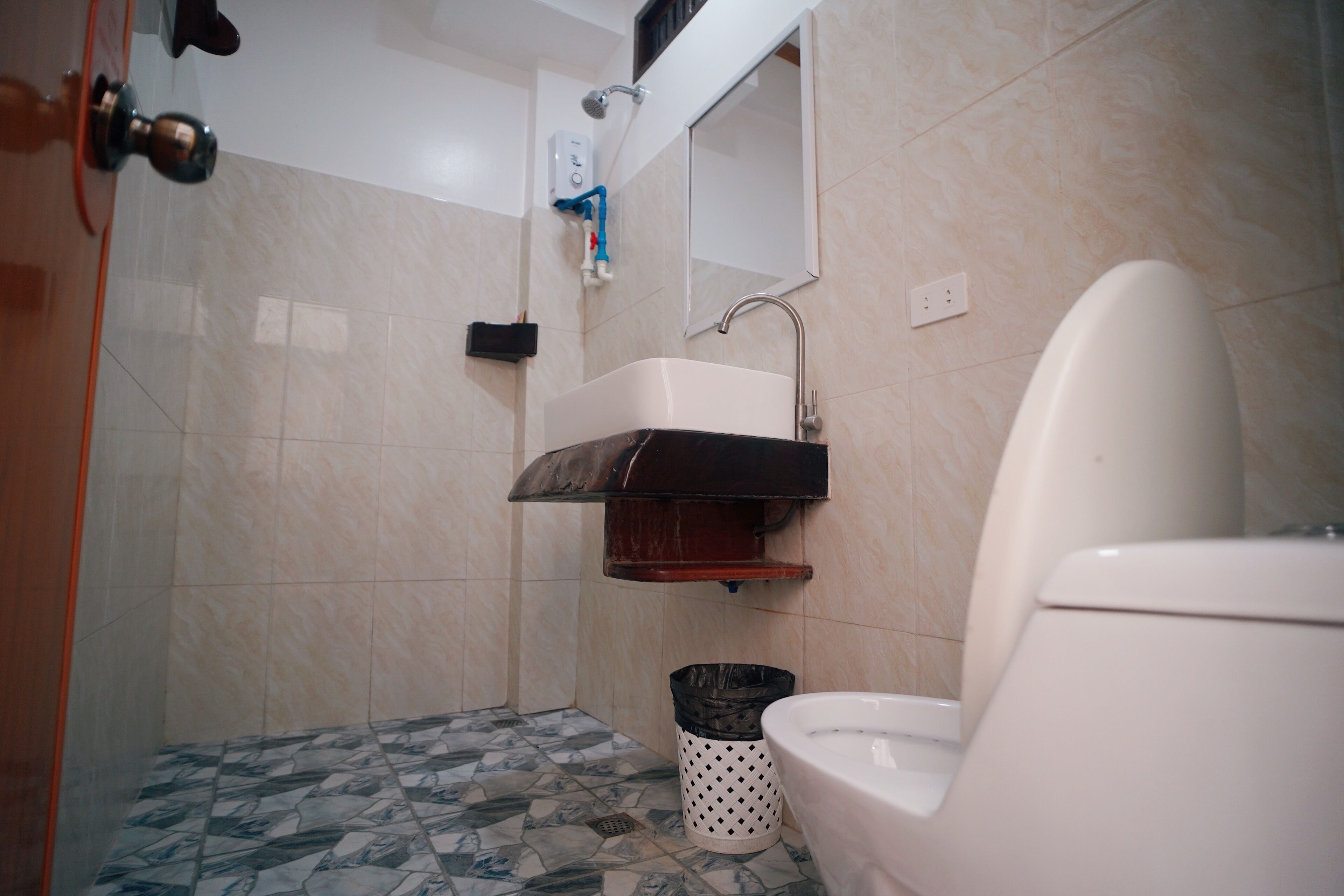 Une salle de bain équipée de toilettes, d’un lavabo, d’une douche et d’un sol carrelé.