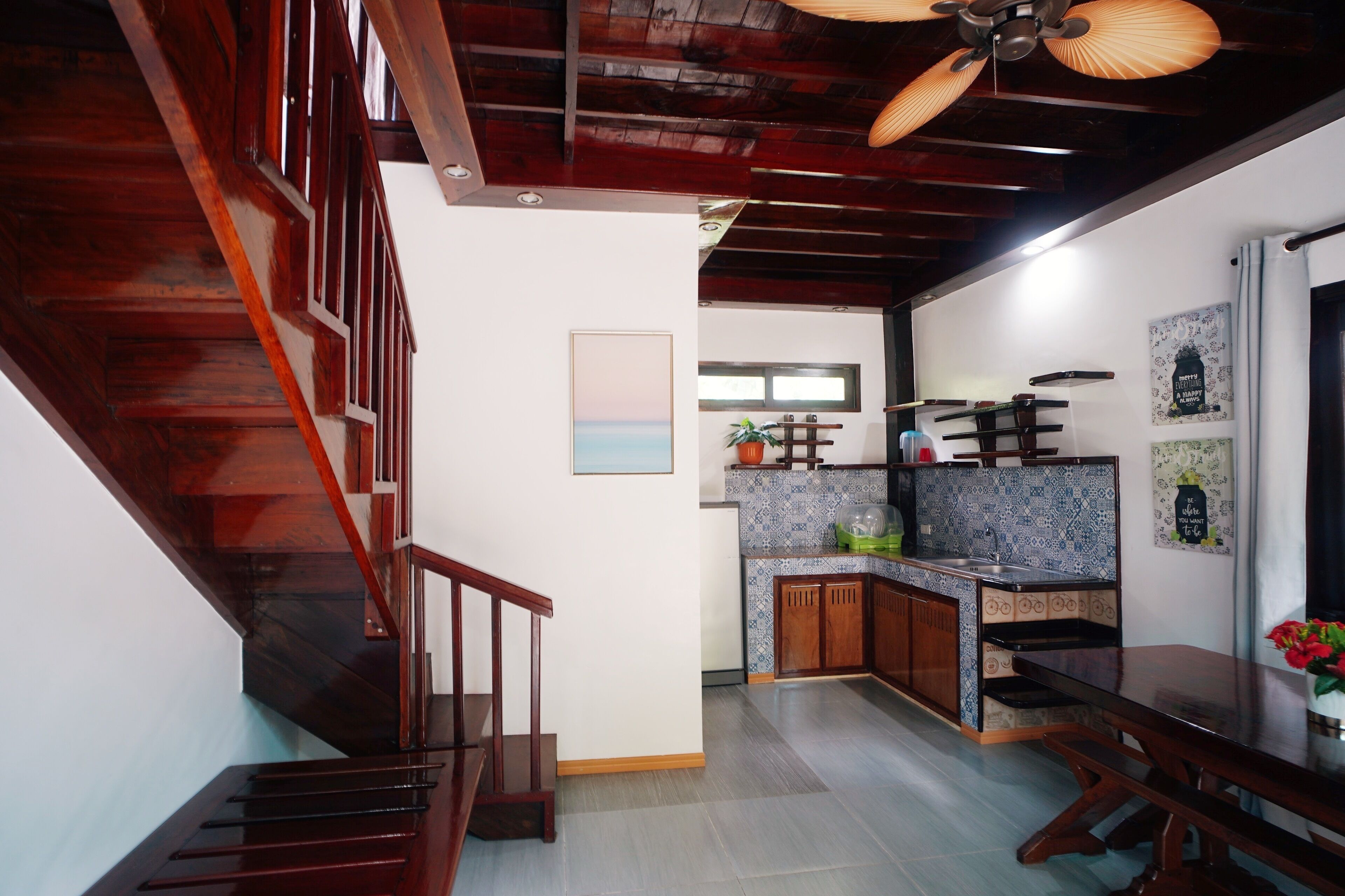 A kitchen with a wooden staircase, a dining area, and a ceiling fan.