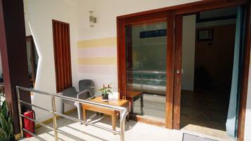 Un balcon avec une table en bois, des chaises et un pot de fleurs.