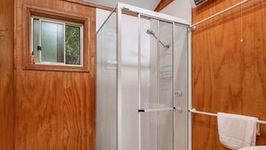 A wooden-paneled bathroom with a glass-enclosed shower, a window, and two sinks. - Canobolas Mountain Two-Bedroom Cabin 1 (Canobolas)