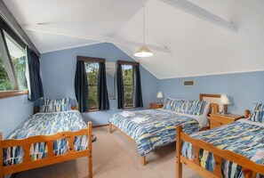A bedroom with two wooden beds, a ceiling fan, and large windows with curtains.