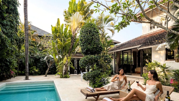 A poolside area with lounge chairs, a swimming pool, and lush greenery. - Villa White Orchid (Seminyak)