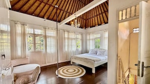 A room with a bed, a chair, a round rug, and a door with a view of the outside. - Villa White Orchid (Seminyak)