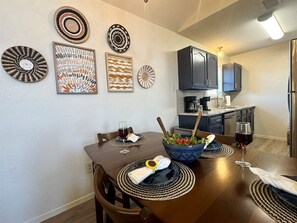 A dining area with a wooden table, chairs, and a bowl of salad. - Baylor House - Stylish Abilene Getaway (Abilene)