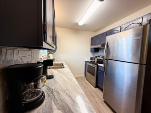 A kitchen with a built-in coffee maker, a stainless steel refrigerator, and a microwave. - Baylor House Stylish Abilene Getaway (Abilene)