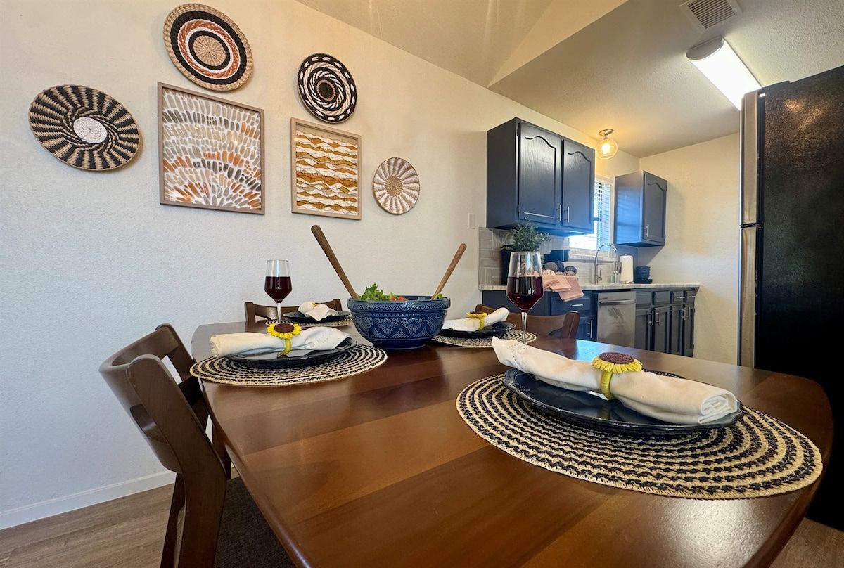 Un espace repas avec une table en bois, des chaises et une cuisine en arrière-plan.