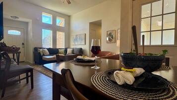 A dining area with a table set for two, a ceiling fan, and a view of the living room.