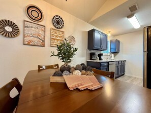 A dining area with a wooden table, chairs, and a plant centerpiece. - Baylor House Stylish Abilene Getaway (Abilene)