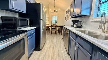 A kitchen with a microwave, stove, refrigerator, and a dining area with a table and chairs.