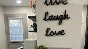 A kitchen area with a countertop, a wall-mounted sign that reads 'live laugh love,' and a potted plant. - Carriage House - Modern Downtown Studio (Abilene)