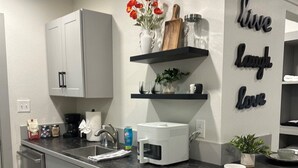 A modern kitchen with a central island, white cabinetry, and decorative wall art. - Carriage House - Modern Downtown Studio (Abilene)