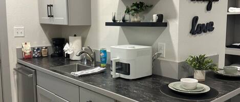Una cocina moderna con una isla central, armarios blancos y detalles decorativos en la pared.