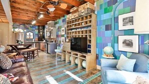 Un salon chaleureux avec un plafond en bois, un canapé, un téléviseur et une bibliothèque.