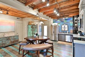 Una cucina moderna con zona pranzo, travi a vista in legno e pavimento colorato.