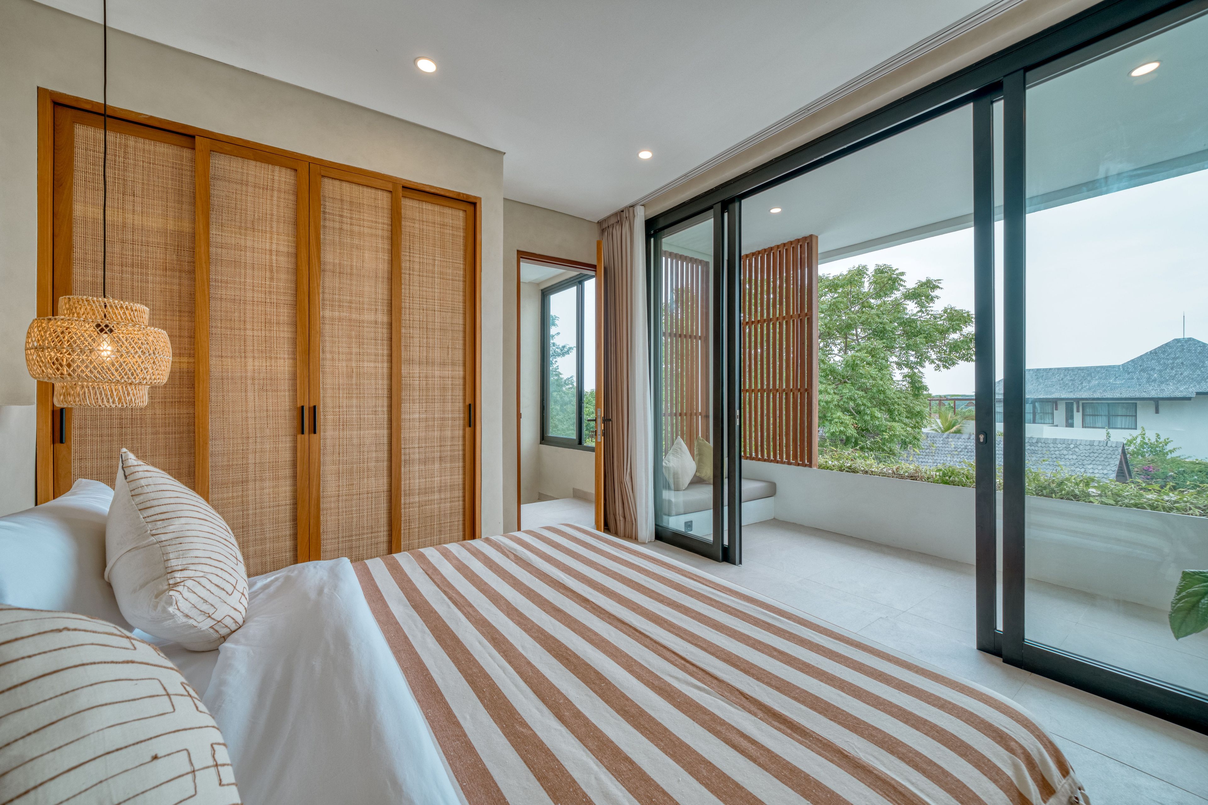 Een moderne slaapkamer met een groot bed, een bedlampje en uitzicht op het omliggende landschap.