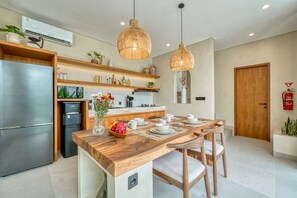 Una cocina moderna con una isla integrada, electrodomésticos de acero inoxidable e iluminación colgante.