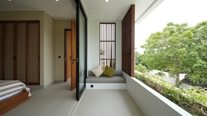 Una camera da letto moderna con un letto grande, un angolo relax con cuscini e un balcone con piante.