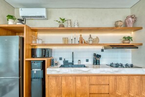 Une cuisine moderne dotée d’un réfrigérateur en acier inoxydable, d’un four à micro-ondes encastré, d’un distributeur d’eau et d’armoires en bois.