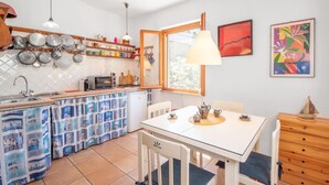 Una cocina compacta con zona de comedor, una ventana y un cuadro abstracto y colorido en la pared.
