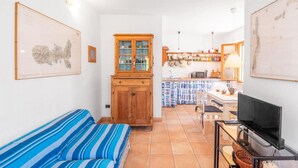Una sala de estar acogedora con un sofá a rayas, un aparador de madera y un televisor sobre un mueble.