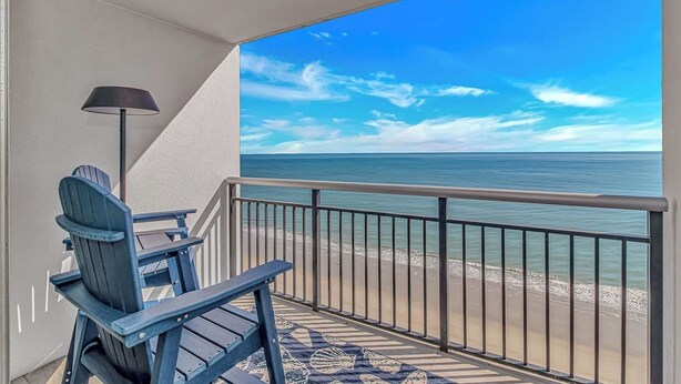 A balcony with a view of the ocean, a chair, and a lamp. - Oceanfront 2BR Retreat | 17th Floor + Balconies (Myrtle Beach)