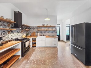 A modern kitchen with a black refrigerator, wooden countertops, and patterned backsplash. - Casa Verde | Historic House For 6 @ San German (San German)
