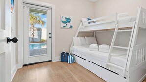 Een kamer met een stapelbed, een deur naar een zwembad en een tas op de vloer.