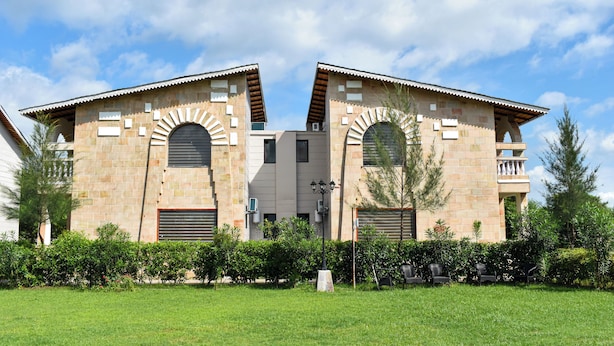 A building with two symmetrical wings, arched windows, and a central entrance. - Amaris Greens Resort (Ramnagar)