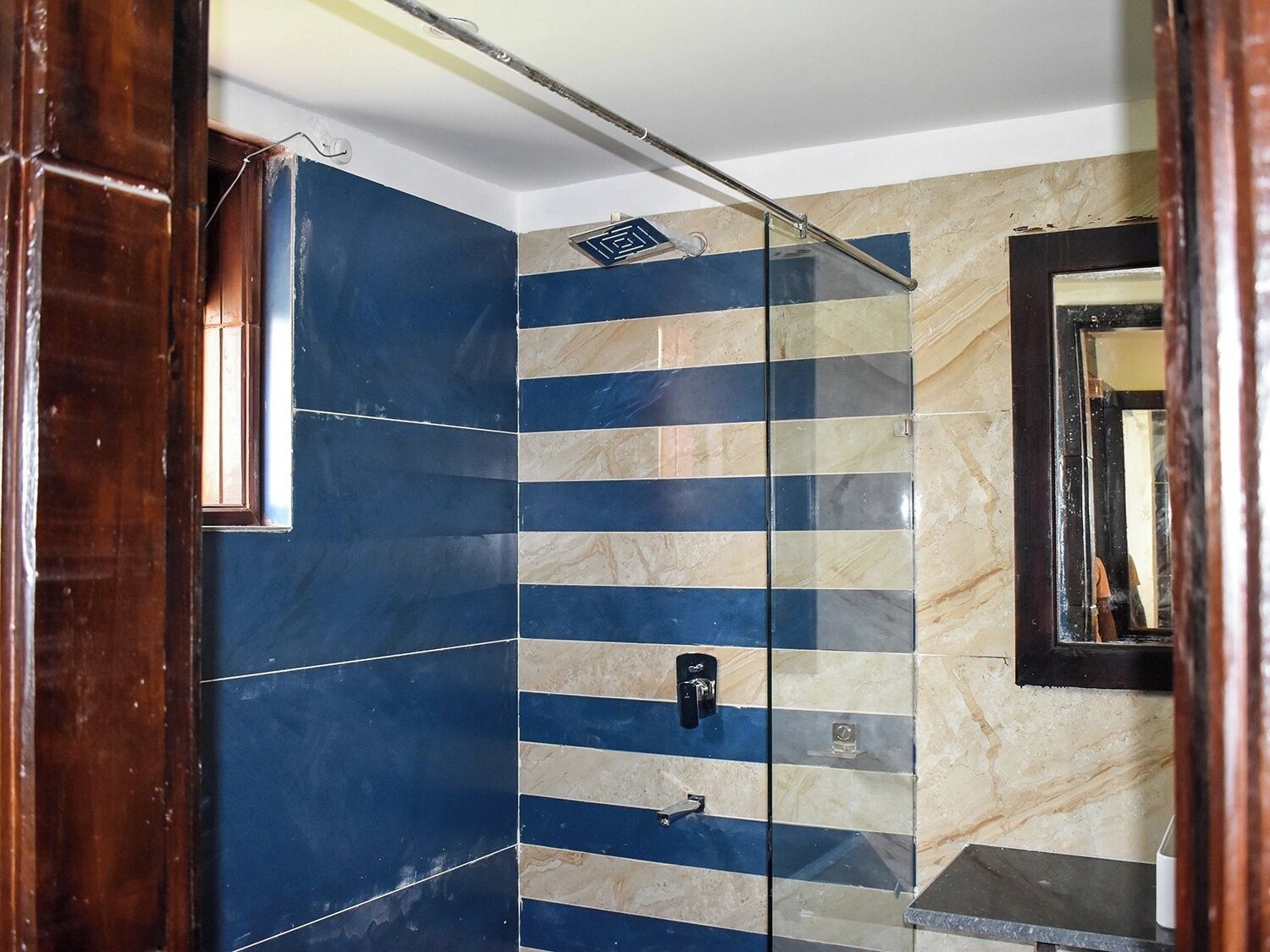 A bathroom with a shower area, a mirror, and a door.