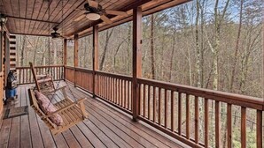 A wooden deck with a swing chair and a ceiling fan, overlooking a forested area. - Mountain Heaven - Hot Tub - Pet Friendly - Long Range Mountain Views - Fire Pit (Blue Ridge)