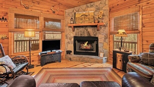 A cozy cabin interior with a stone fireplace, wooden walls, and a leather sofa. - Mountain Heaven - Hot Tub - Pet Friendly - Long Range Mountain Views - Fire Pit (Blue Ridge)