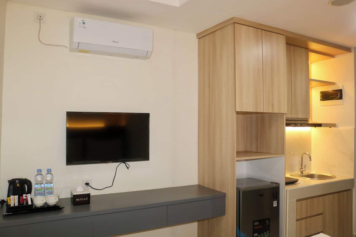 A modern kitchen with a built-in microwave, a sink, and a flat-screen TV mounted on the wall.