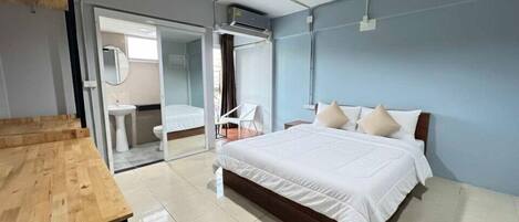 A bedroom with a bed, a wooden table, a sink, and a chair.
