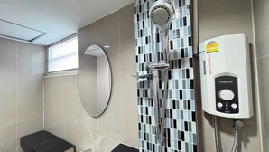 Un baño con ducha, inodoro y ventana.