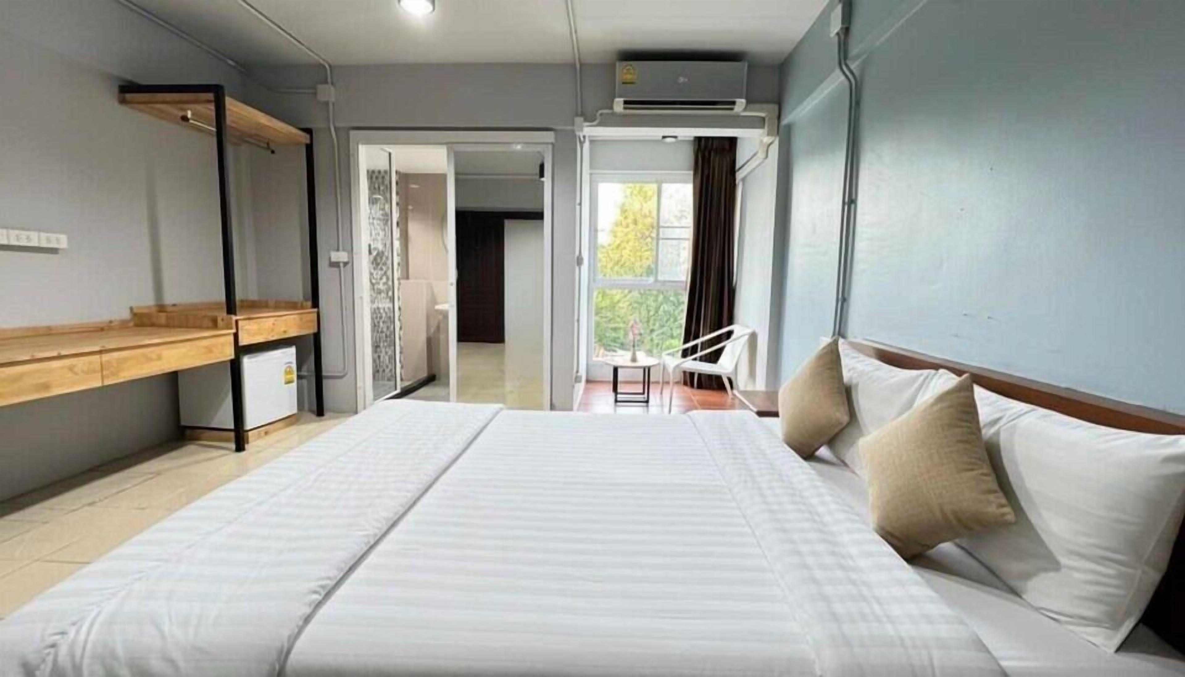 Une chambre d’hôtel moderne avec un grand lit, un bureau en bois et une vue sur l’extérieur.