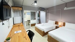 Habitación de hotel con dos camas, un escritorio, una silla, un televisor y aire acondicionado.